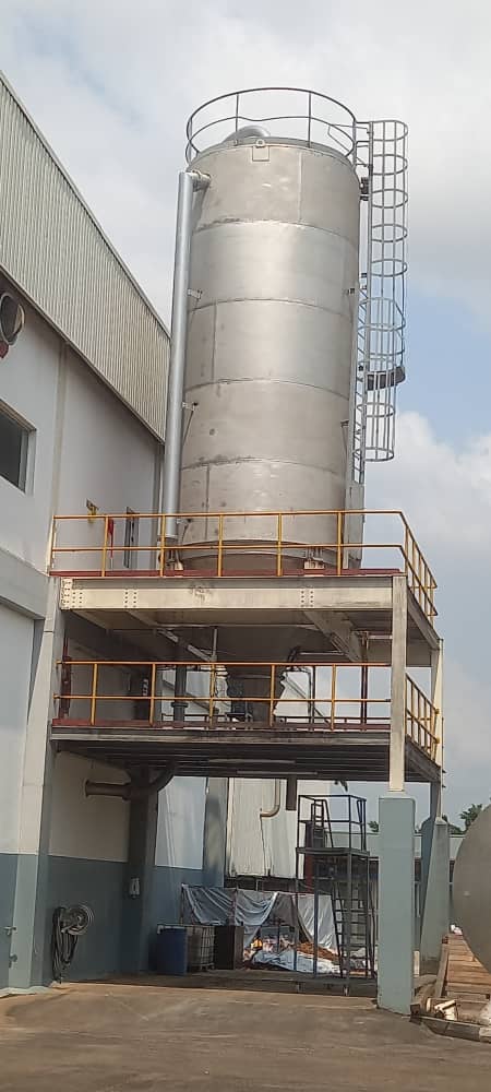 Tall vertical fluid mixing vessel outside building